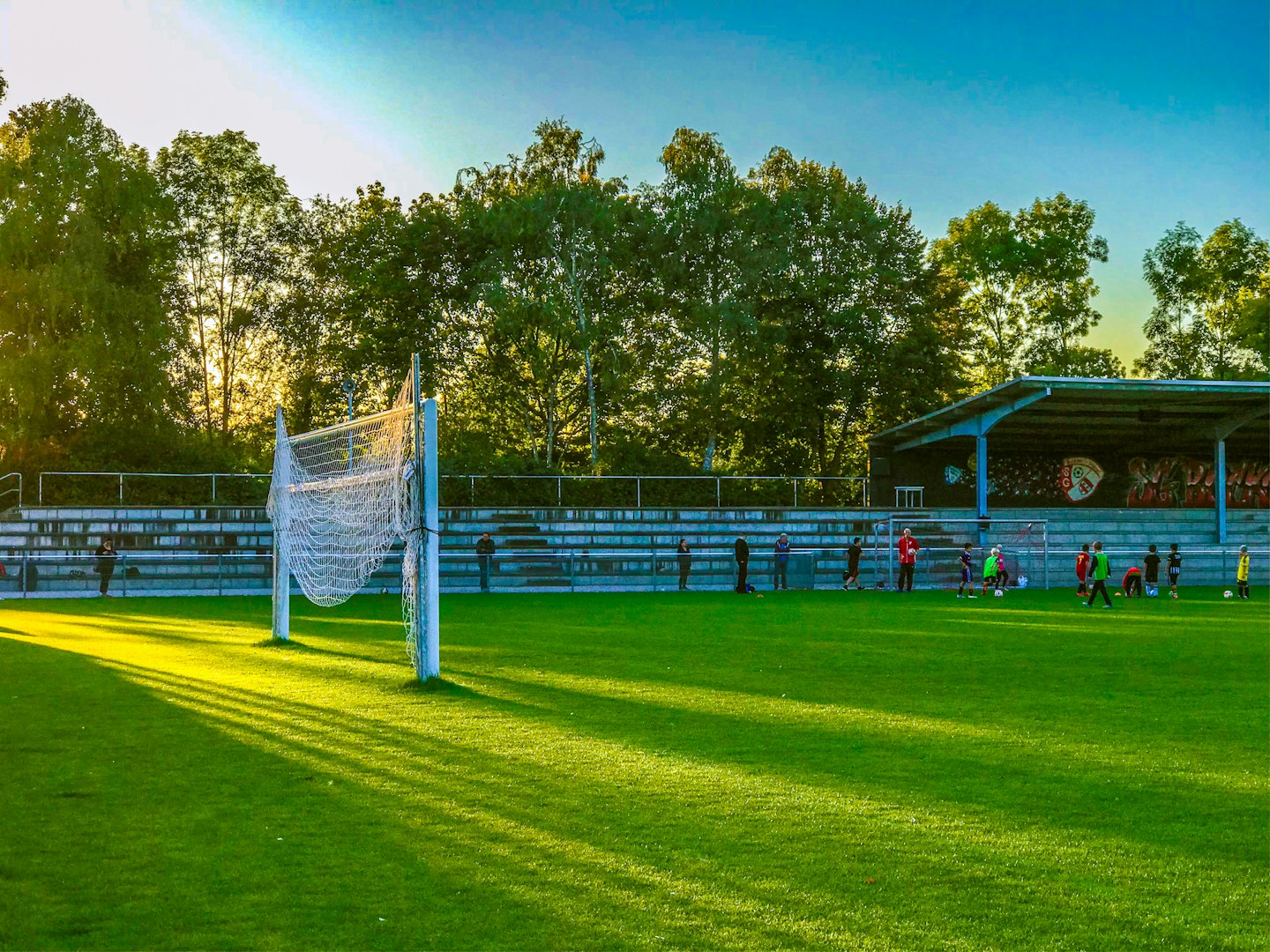 Bambini giocano a calcio in un campo soleggiato vicino alla porta.